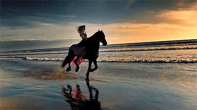 An animated gif of a woman riding a horse on a beach