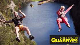 two people hanging in harnesses over a lake at adrenaline quarry in cornwall