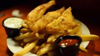 fish and chips on a plate with two dipping sauces
