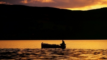 silhouette of fishermen on his boat at sunset