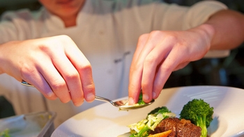 chef placing finishing touches on a plate of food