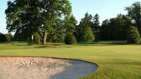 scenic golf course surrounded by trees with sand bunker