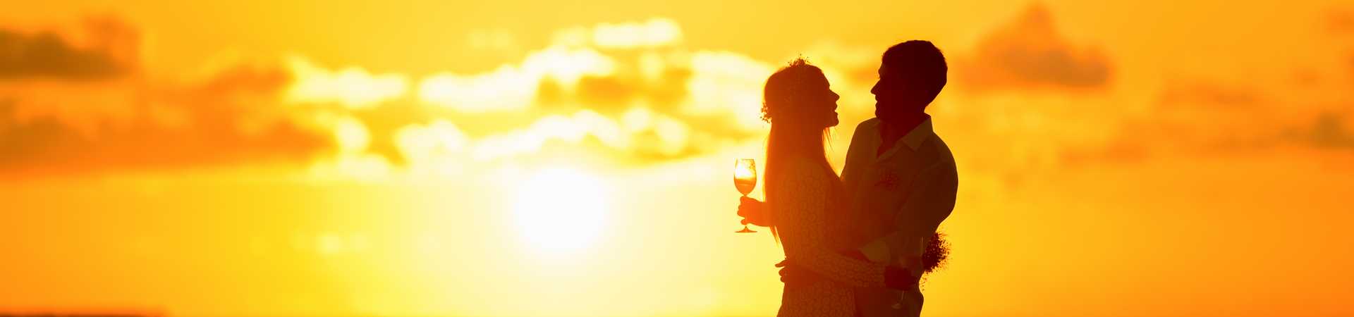 couple on the beach at sunset hugging and drinking wine